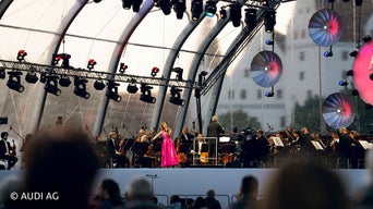 Violinistin im pinken Kleid vor Orchestra auf Bühne