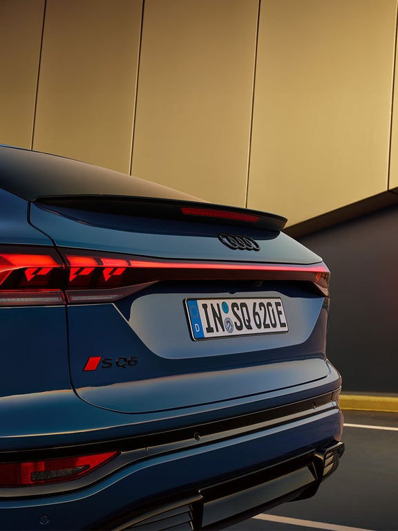 Nahaufnahme der Rückleuchten und des SQ6-Logos an einem blauen Audi SQ6 Sportback e-tron.