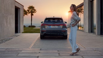 Frau steht hinter ihrem Audi Q8 e-tron