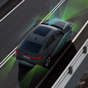 Der Q6 Sportback e-tron von schräg oben. Vom Heck und der Front aus unterteilen grüne und blaue Vektoren die Flächen hinter und vor dem Fahrzeug.