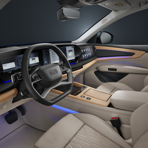 Vue de l'habitacle du SUV Audi Q7 depuis le côté conducteur, mettant en avant le volant, les écrans numériques et le voyant d'interaction bleu.