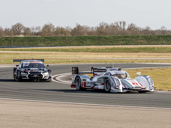 A picture showing two race cars from Audi Sport racing legends being demonstrated on the track in Neuburg.
