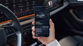 A hand holding a mobile phone with its screen the focal point displaying the myAudi app