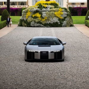 ヴィラの砂利敷きの車道で、黄と白の花の装飾を背景にしたAudi Nuvolariのフロントビュー