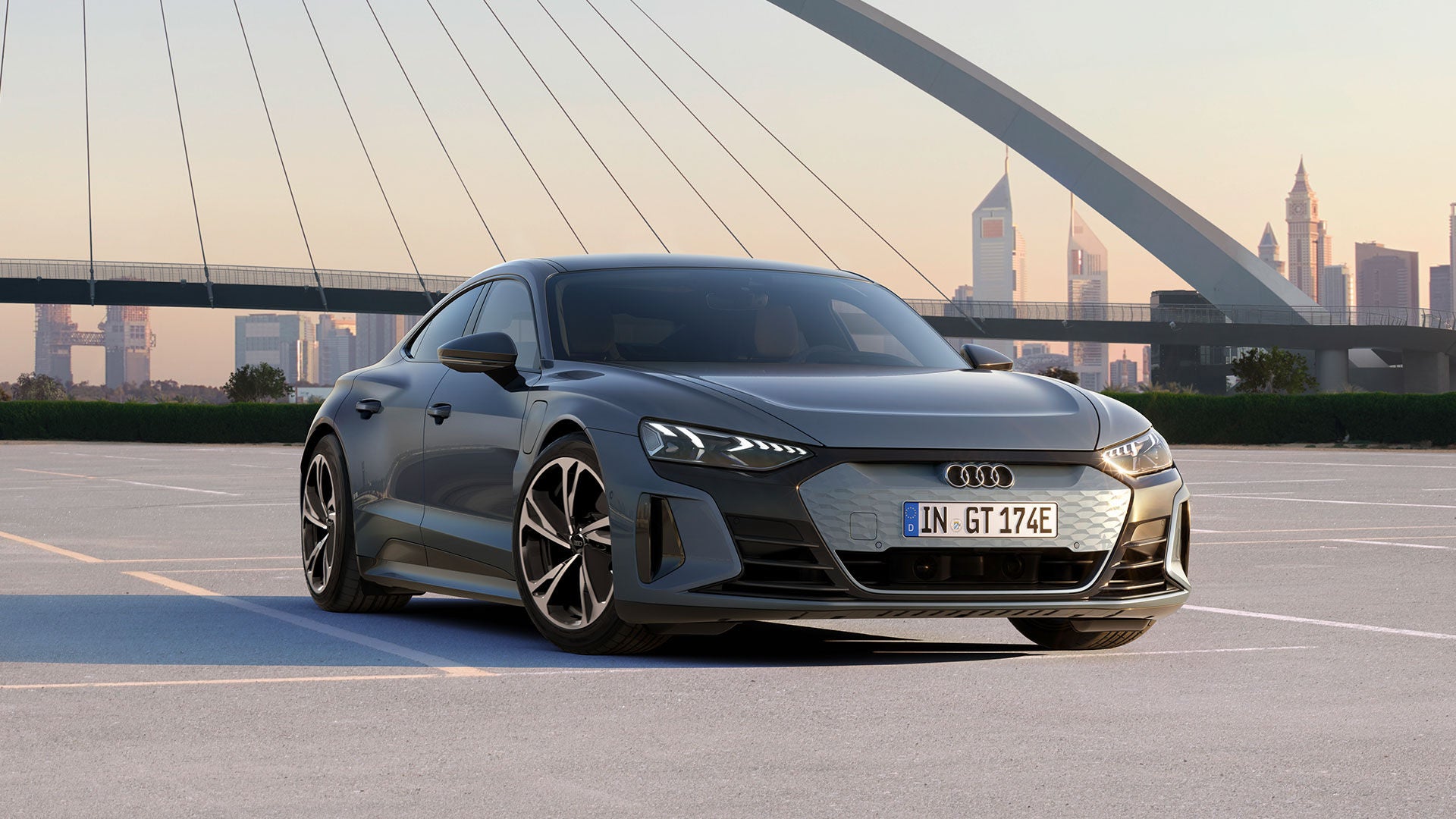 Ein grauer Audi e-tron GT vor einer Brücke, dahinter sieht man eine Skyline.