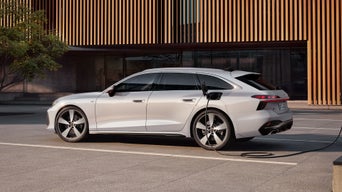 L’A6 Avant e-tron est garé à côté d’une maison futuriste, à côté d’une station de recharge.