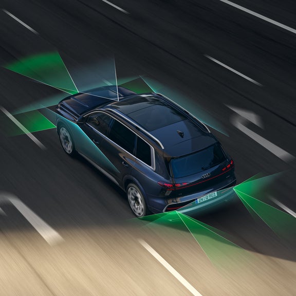 Der Audi Q9 SUV von schräg oben auf einer vierspurigen Straße. Vom Heck und der Front aus unterteilen grüne und blaue Vektoren die Flächen hinter und vor dem Fahrzeug.