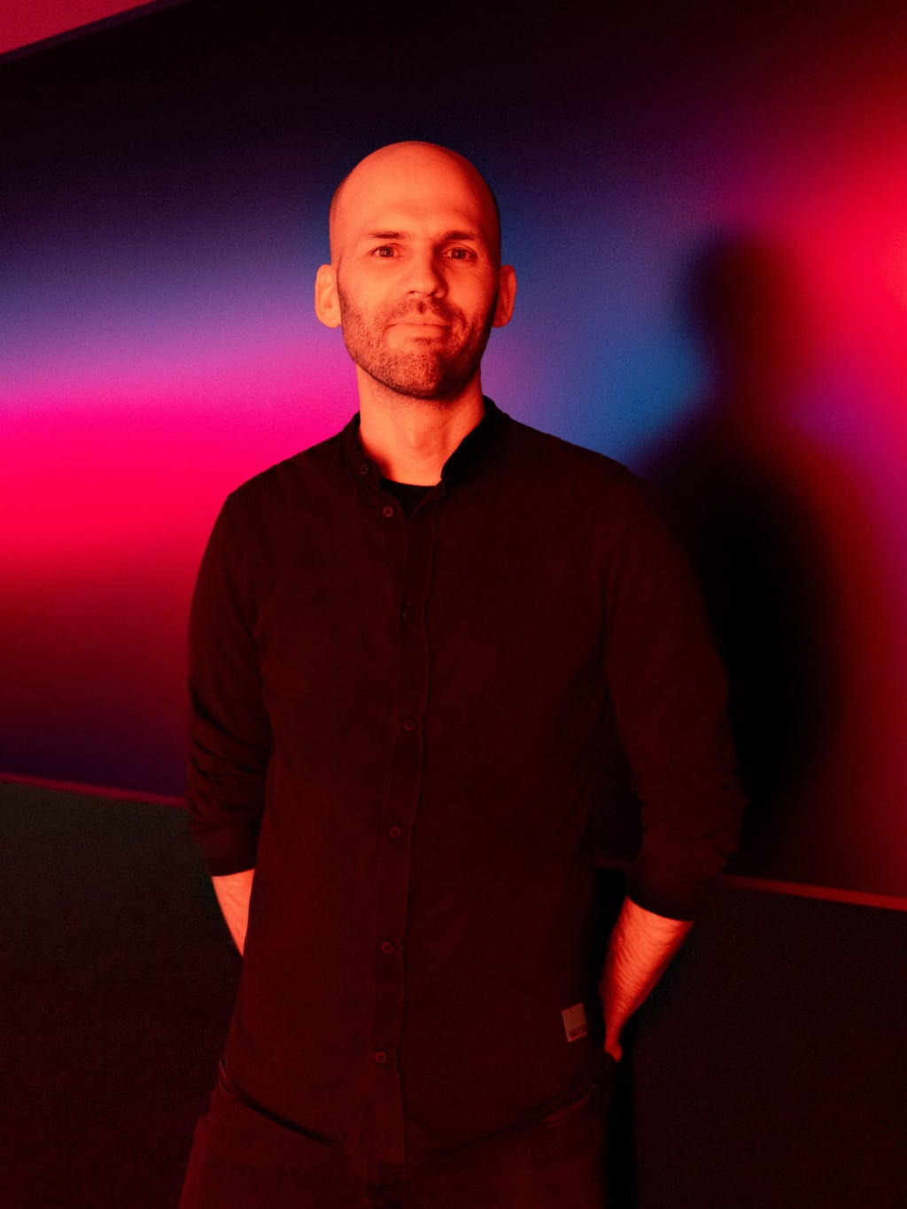 Portretfoto van Audi-designer Christoph Häußinger tegen een achtergrond van rood en blauw licht.