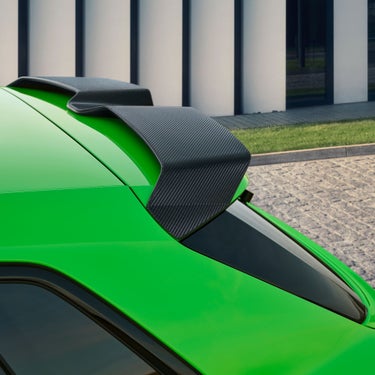  Close-up of a green Audi RS3 Sportback car's rear with a carbon fiber spoiler.
