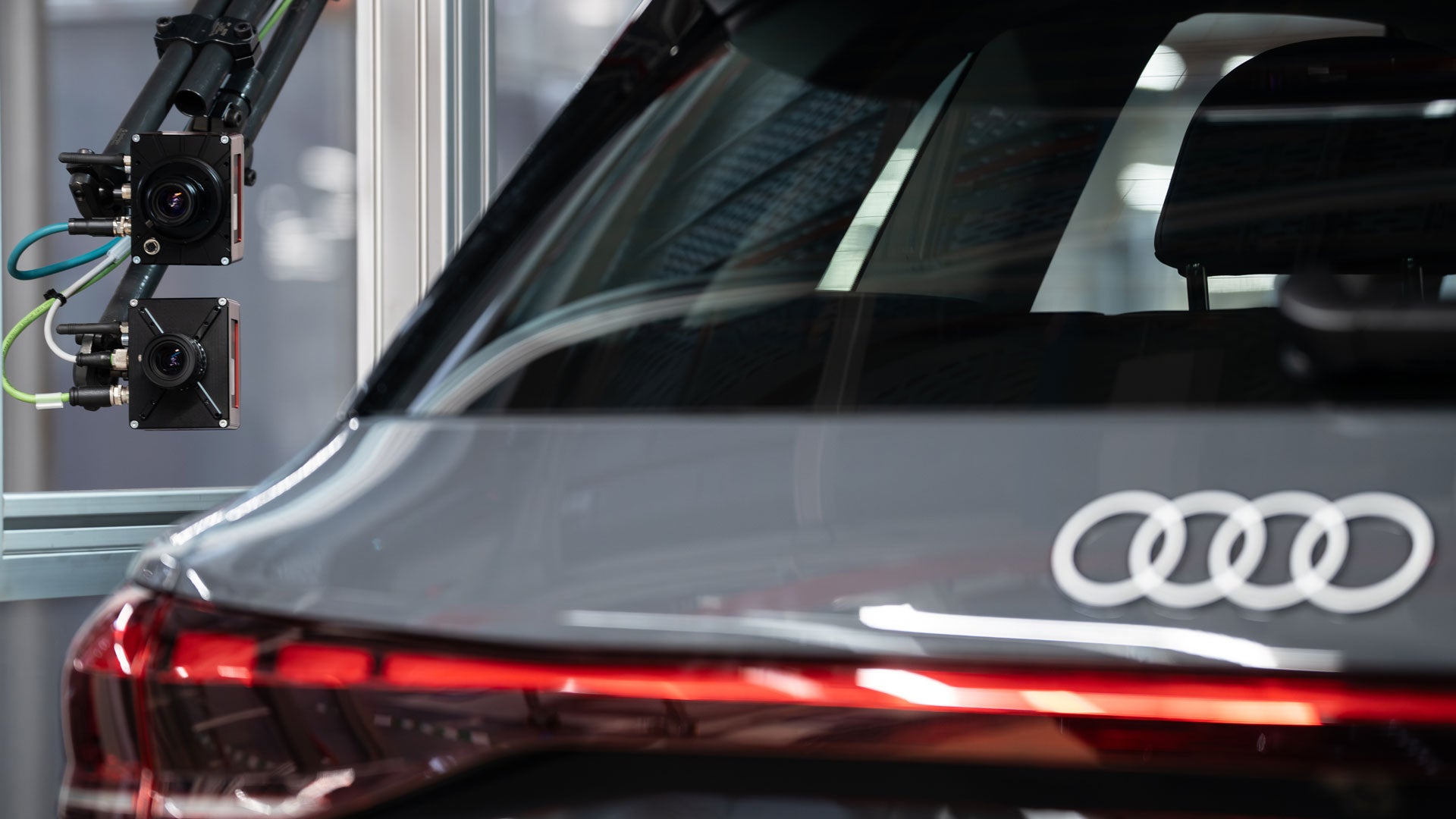 Grauer Audi angeschlossen an externe Kameras und Sensoren in einer Produktionshalle