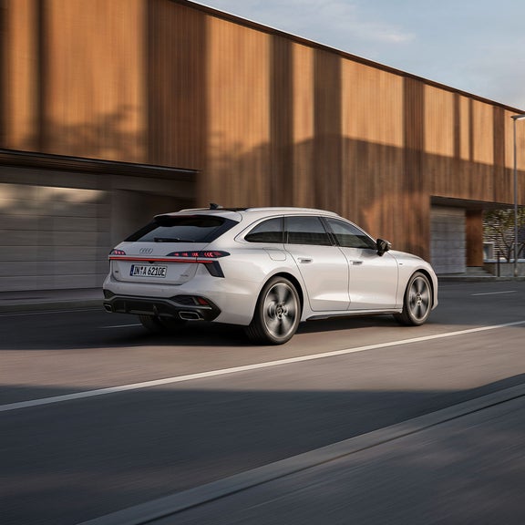A white Audi A6 Avant e-hybrid driving in an urban street
