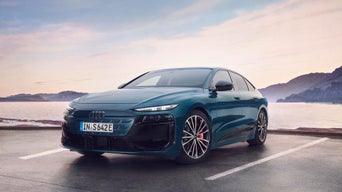 Grüner Audi Elektro-Sportwagen am See mit Bergen im Hintergrund.