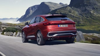 Schräges, hinteres Seitenprofil des roten SQ5 Sportback, welcher auf einer Straße durch die Berge fährt.