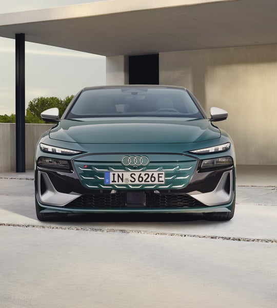 Der S6 Sportback e-tron steht im Frontprofil vor einem modernen Haus.