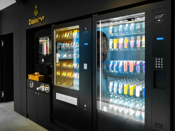 A black vending machine with snacks and drinks and the golden Dallmayr logo