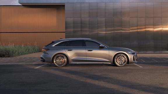 A silver Audi S5 Avant parked outside a building with a metallic facade during sunset.