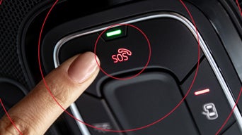 Finger drückt die rot leuchtende SOS-Taste im Innenraum eines Audi-Fahrzeugs.