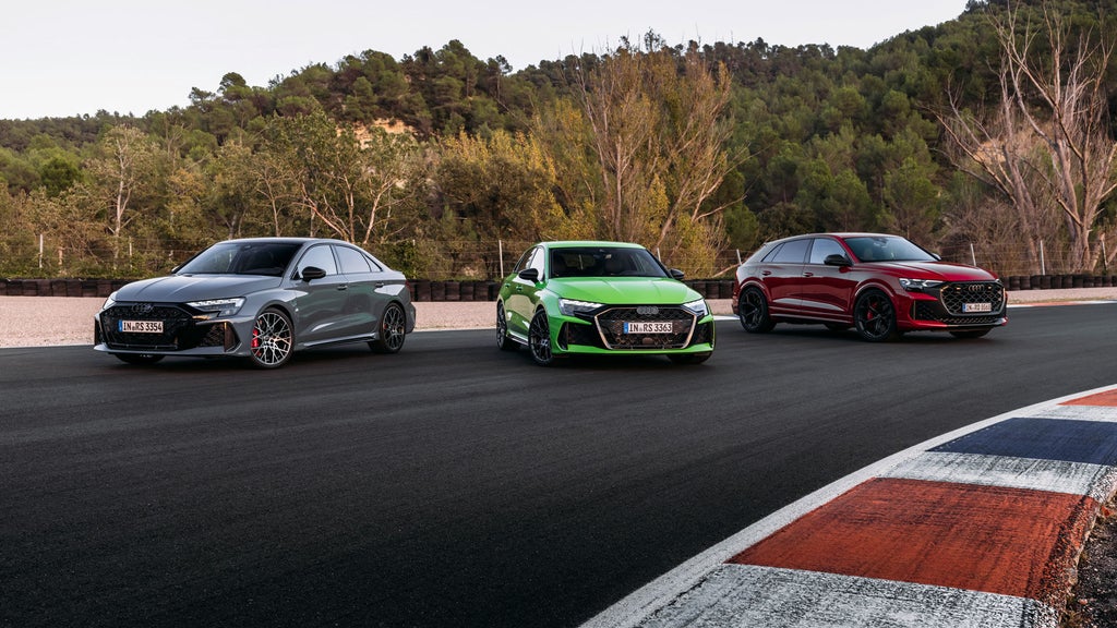 3 Audi RS Modelle stehen nebeneinander aufgefächert auf einer Rennstrecke