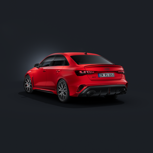 De Audi RS 3 Berline, schuin van achteren gezien tegen een donkere achtergrond.