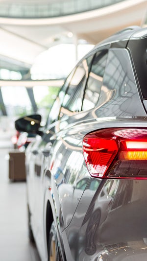 Rear view of a silver Audi Q4 in a modern showroom with light-colored glass facades and other vehicles in the background.