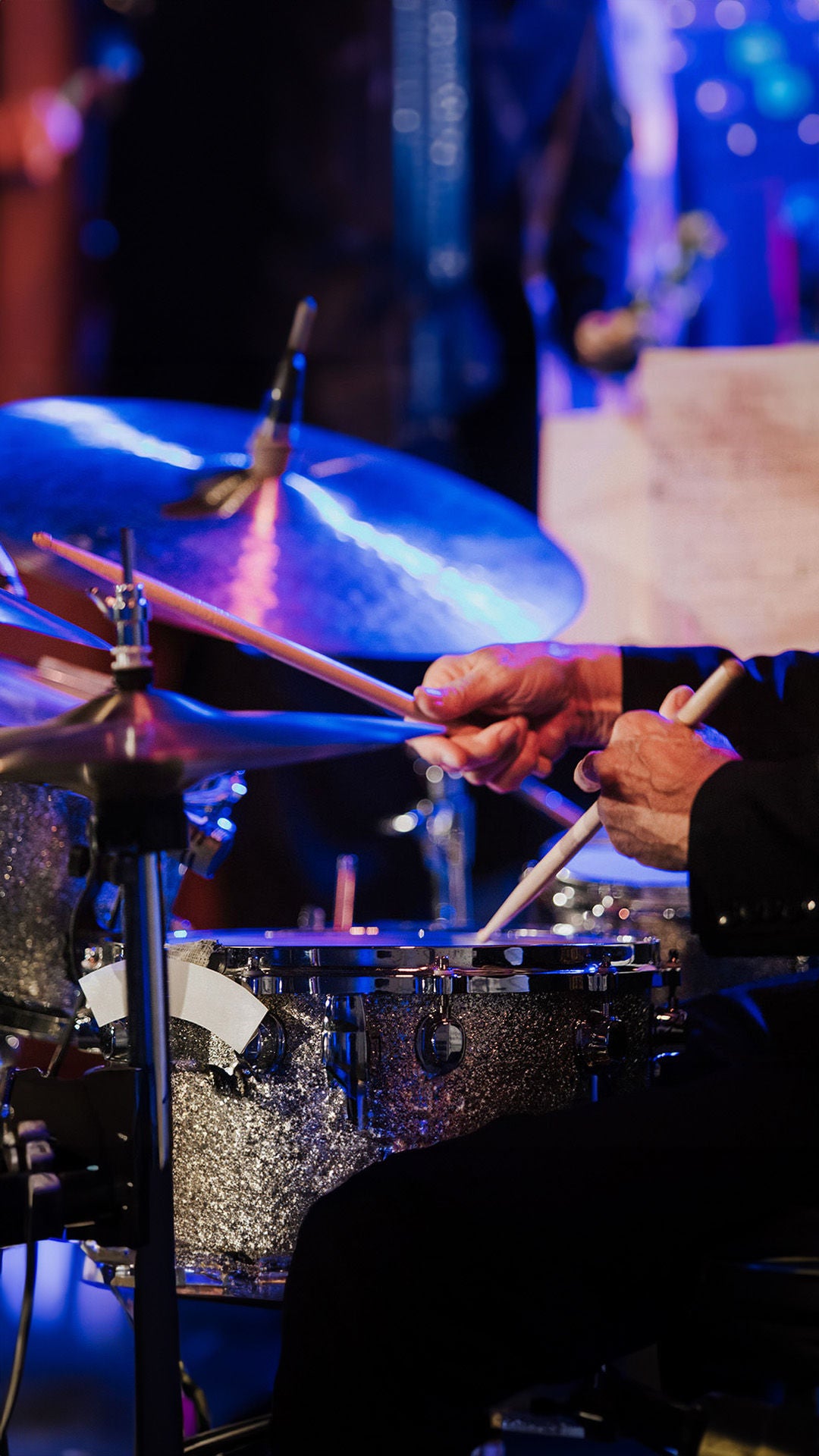 Close-up of a drum set, a person plays with drumsticks on the drums and cymbals.