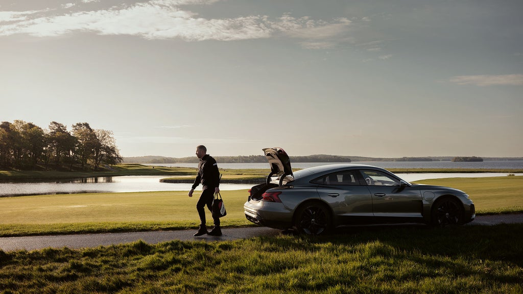 Viktor Gustavsson i med sin Audi e-tron GT vid en golfbana i gryningen.