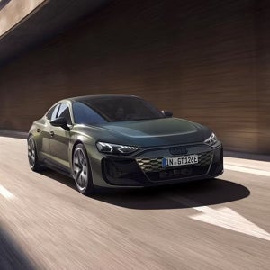 A green Audi car drives in a sunlit tunnel. The design is modern and aerodynamic, conveying speed and elegance. License plate reads "IN GT 126E."