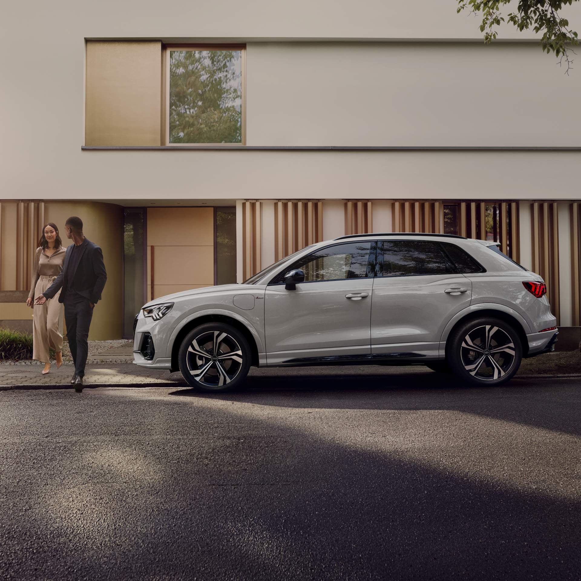 Man standing infront of Audi Q3 on side street.