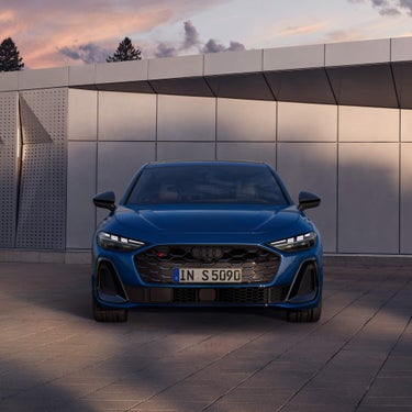 Frontansicht einer blauen Audi S5 Limousine vor heller Wand mit LED-Tagfahrlichtern.