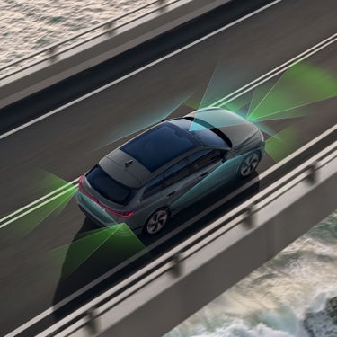 Grauer Audi A6 Avant e-tron auf Straße von oben, grüne und blaue Flächen zeigen Assistenzsysteme.