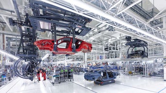 The body of an Audi e-tron GT is guided through the stations using a rail system on the ceiling.