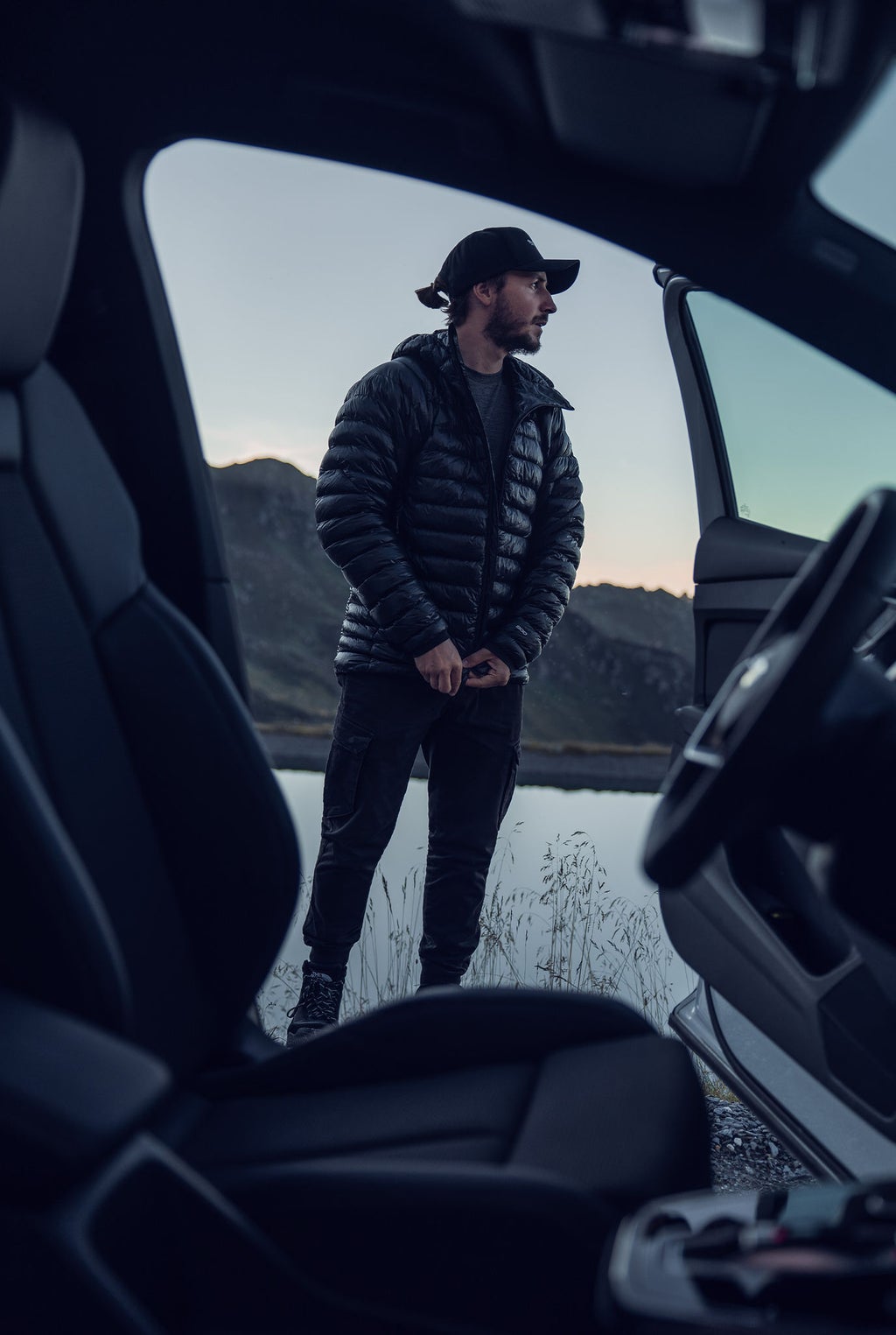 Tom Klocker steht vor einer offenen Autotür und schaut in die Ferne.