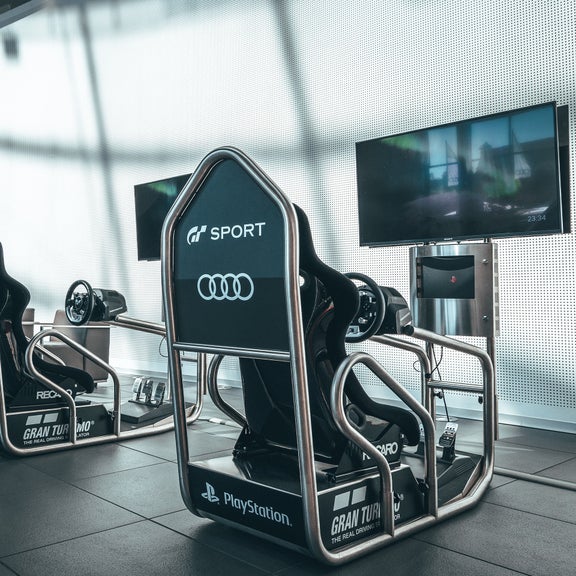 Two Audi racing simulators with steering wheels and monitors in a modern room with Audi branding.