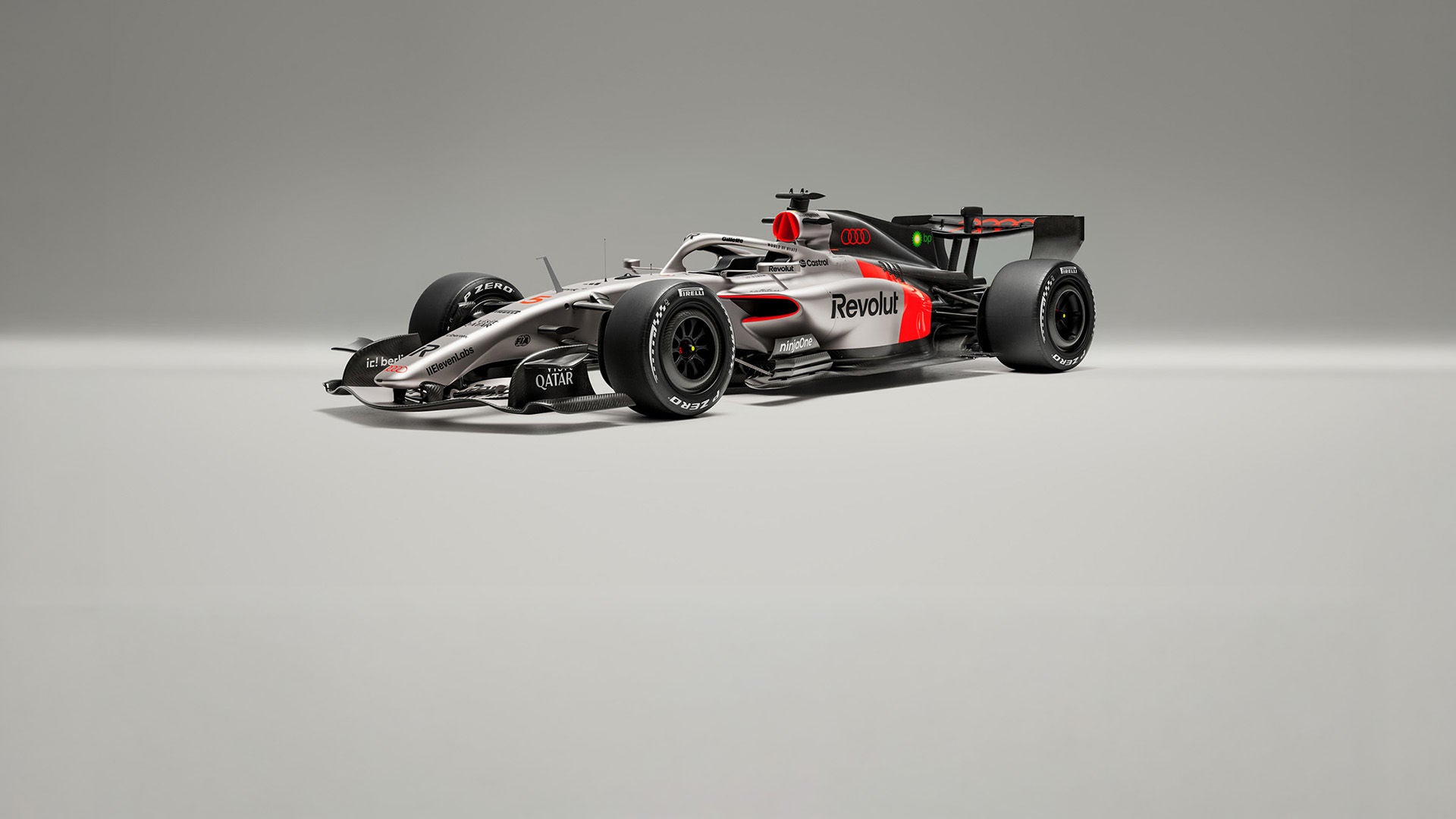 Audi-Formel-1-Rennwagen in Silber-Schwarz mit roten Akzenten und Sponsoren-Logos, freigestellt vor grauem Hintergrund.