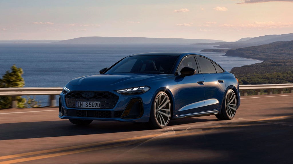The dark blue S5 Saloon drives along a road by the coast.