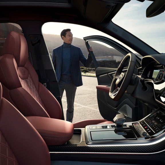 Car interior with red leather seats and open driver's door.