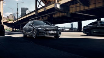 Ein Audi A7 fährt neben einer Brücke her