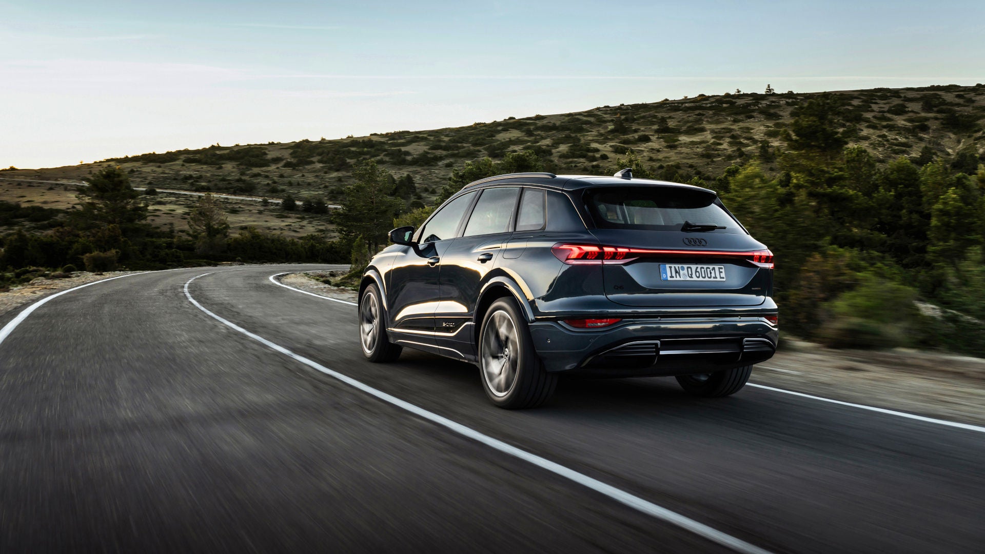 A black Audi Q6 e-tron quattro drives along a country road