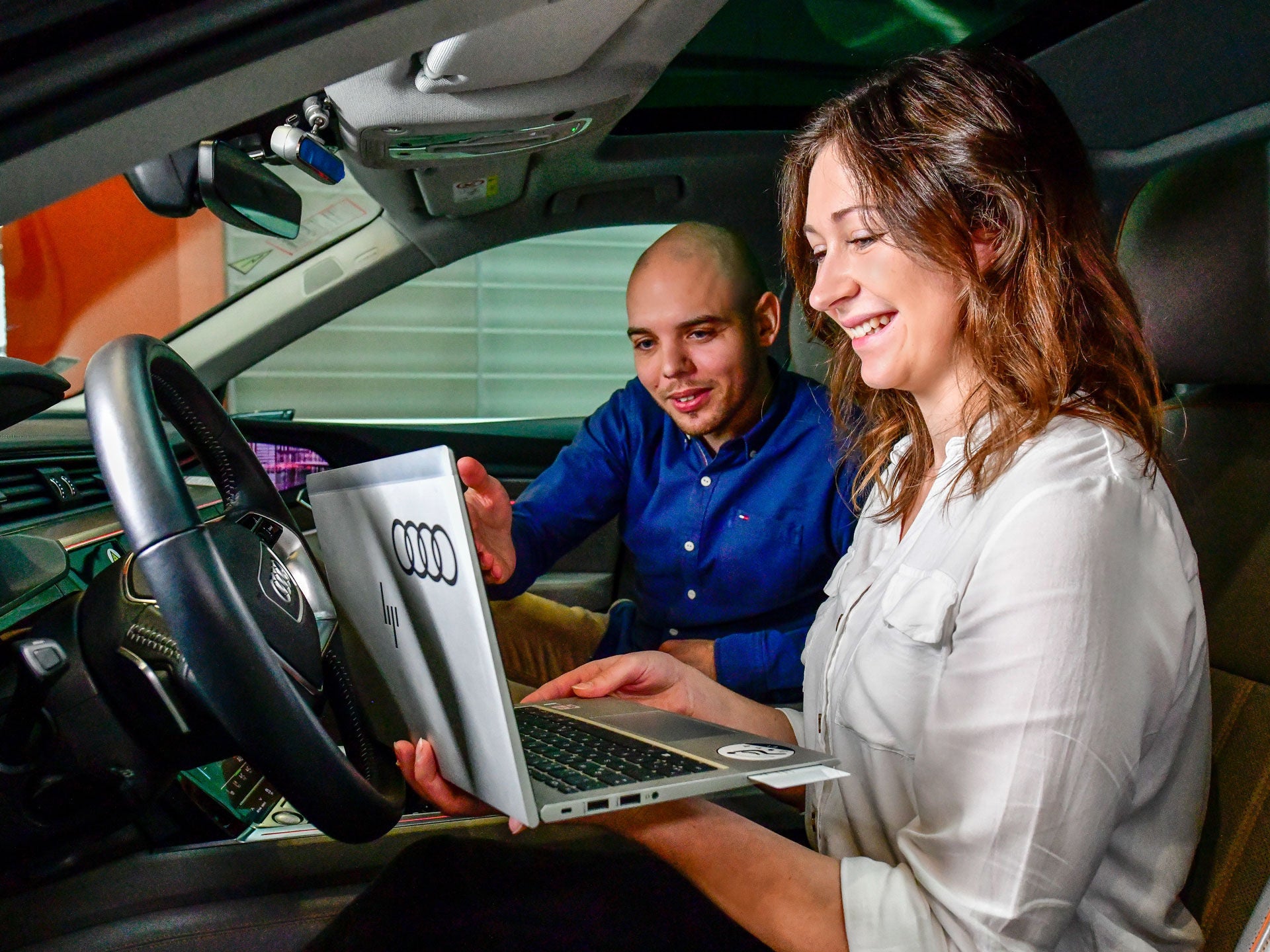 Zwei Personen im Auto sitzend mit Laptop