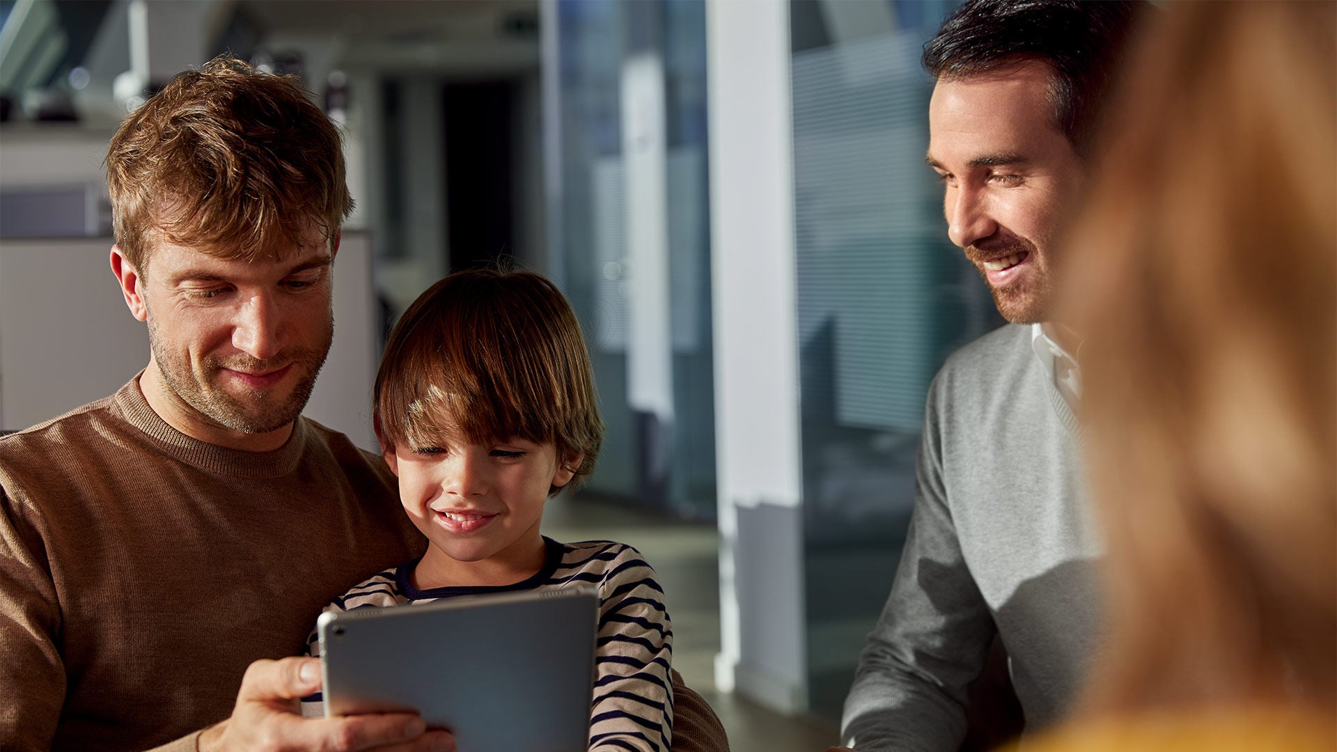A man and a child use a tablet computer in an Audi showroom while a salesman watches.