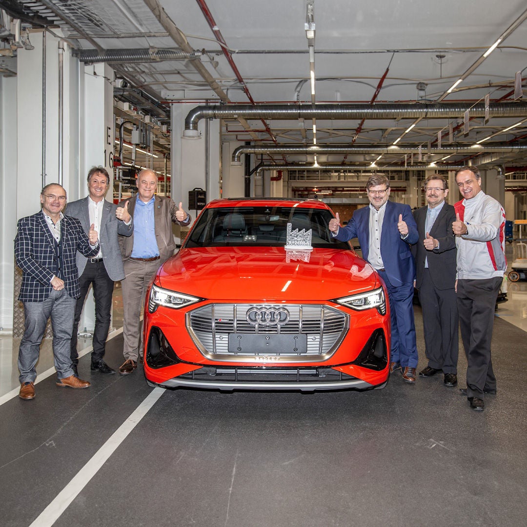 Un groupe d'employés pose devant une Audi dans l'atelier