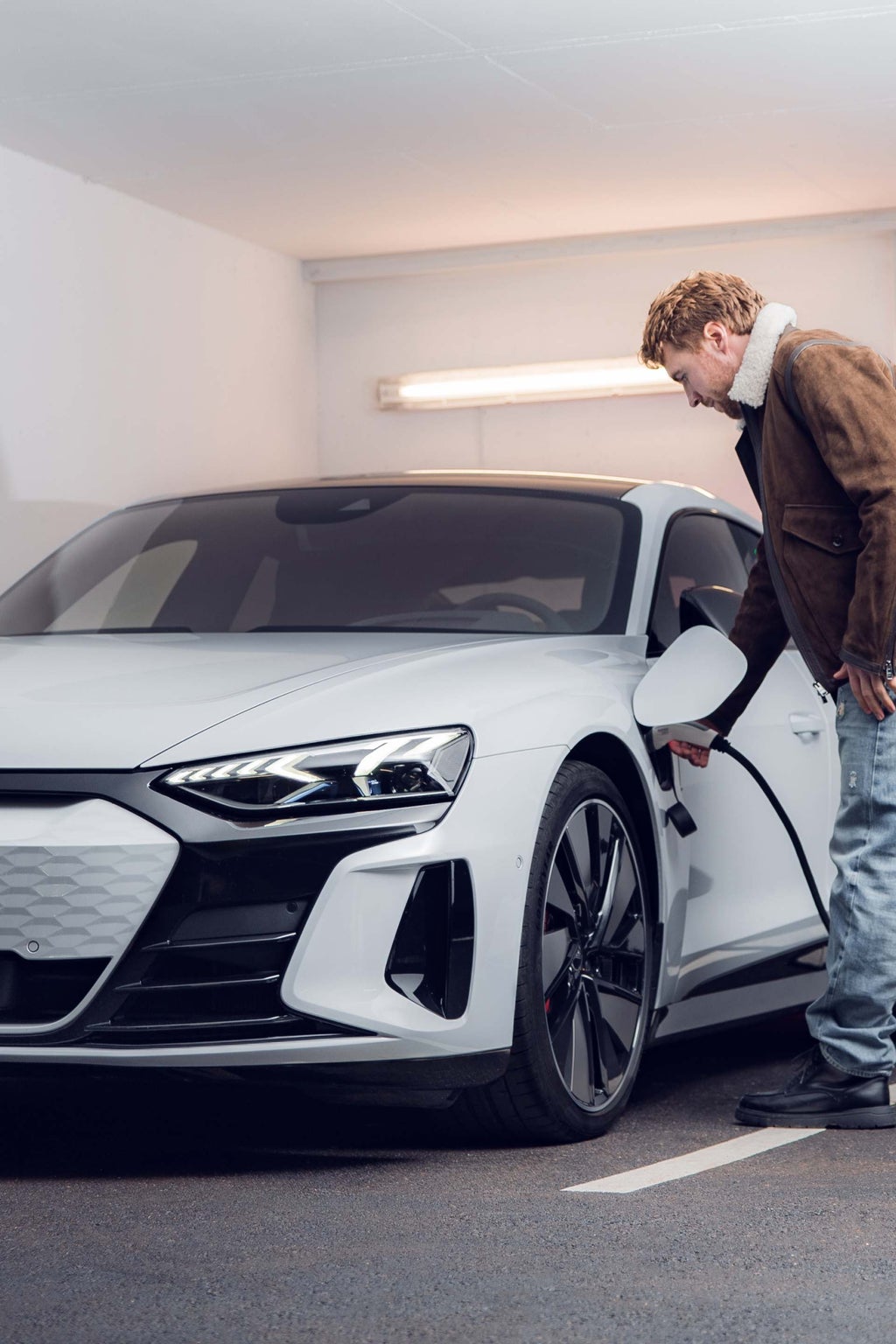 Aleksandr Kilde haalt thuis de laadstekker uit zijn Audi e-tron GT.
