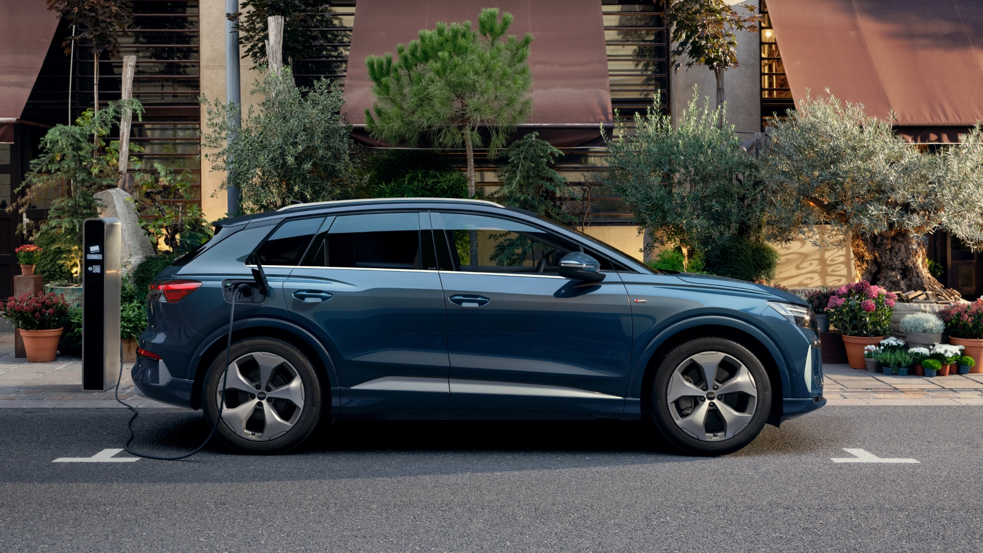 Audi Q3 SUV, an electric vehicle and family SUV, in a green metallic colour driving on a road.
