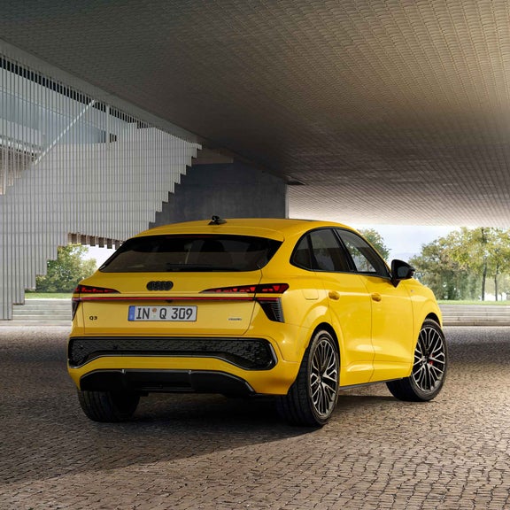 Audi Q3 Sportback from a side front view. The car is parked next to a staircase, presumably under a house in a parking lot.