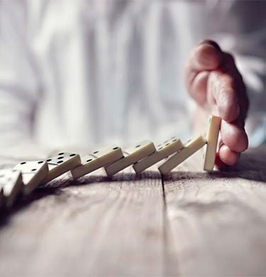 Person stoppt umfallende Dominosteine