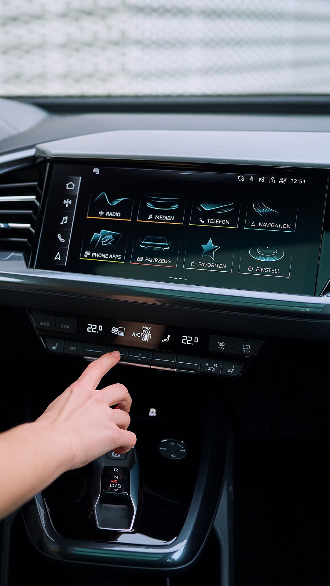 Person bedient Klimasteuerung im Audi-Innenraum mit großem Display und digitalem Bedienfeld.