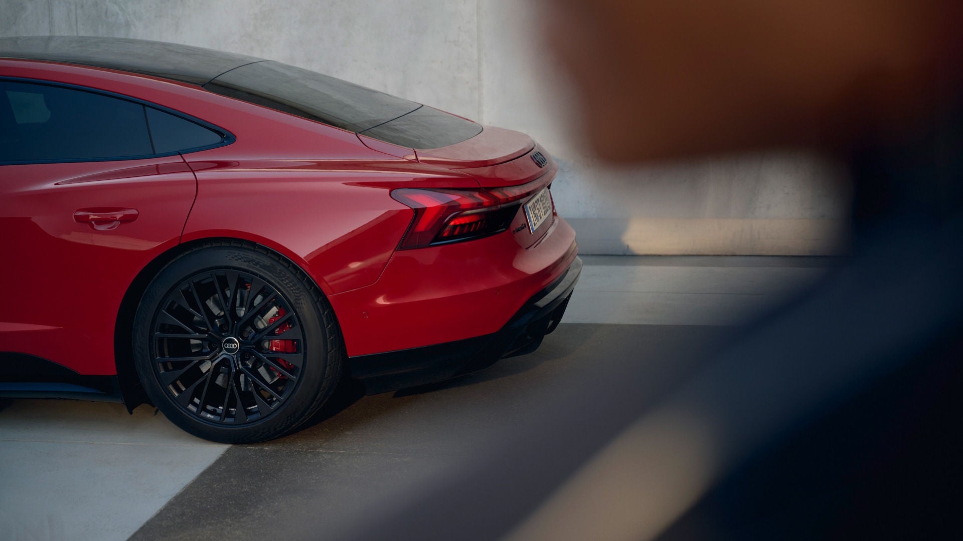 Ein Audi e-tron GT quattro steht geparkt vor einer Wand. Man sieht nur das hintere Drittel des Fahrzeugs.