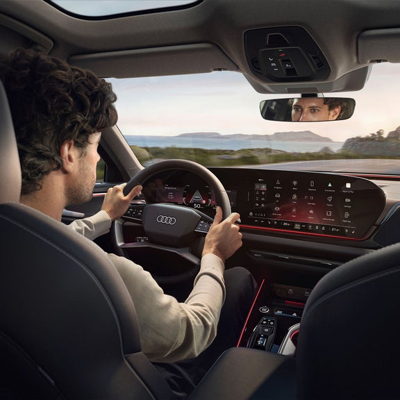Interior view of an Audi from the back seat, while a man is driving
