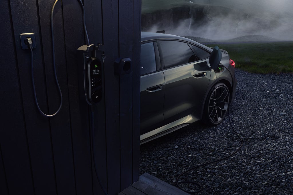Focus on the rear of the RS 5 Saloon, with a charging station in the background.