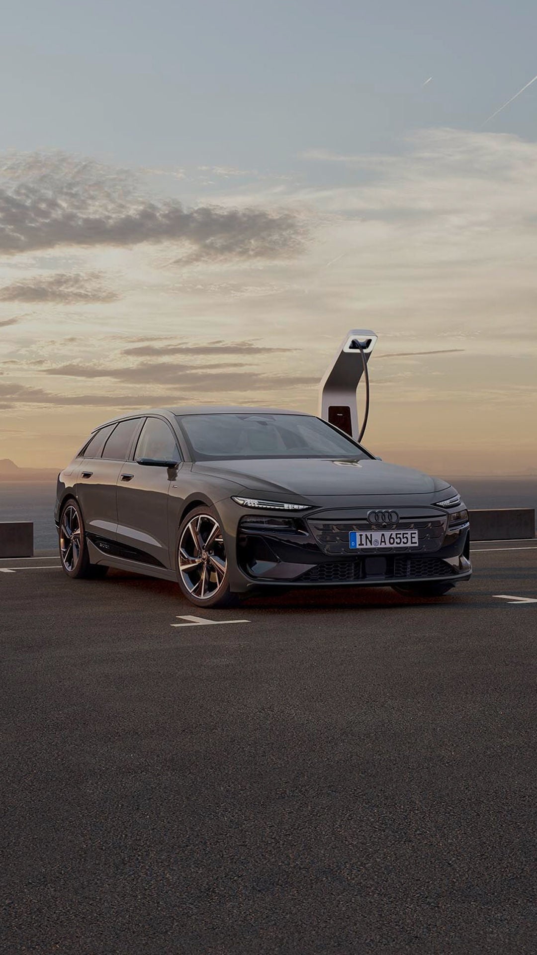 Audi electric car parked in on dusty road with sunsetting in the background
